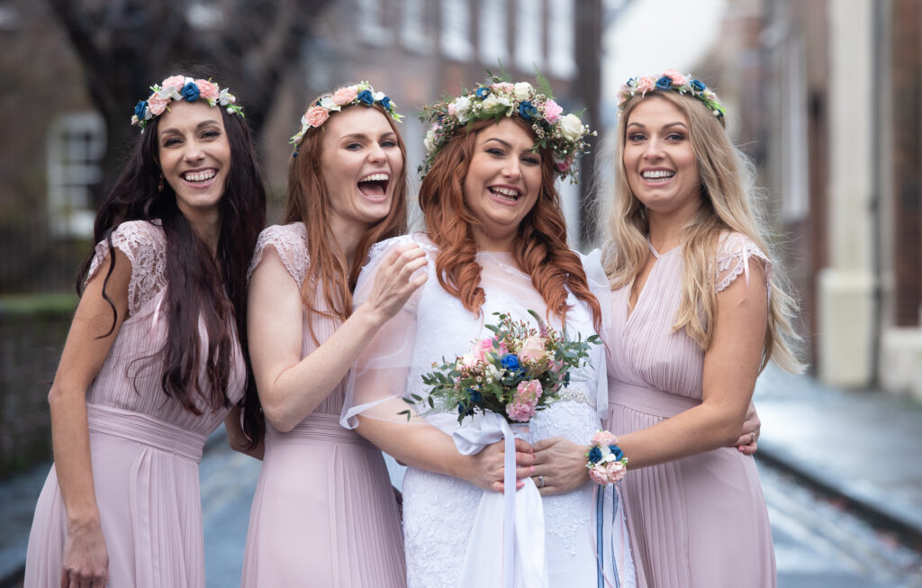 Bridesmaids wearing pink and laughing during group photographs 