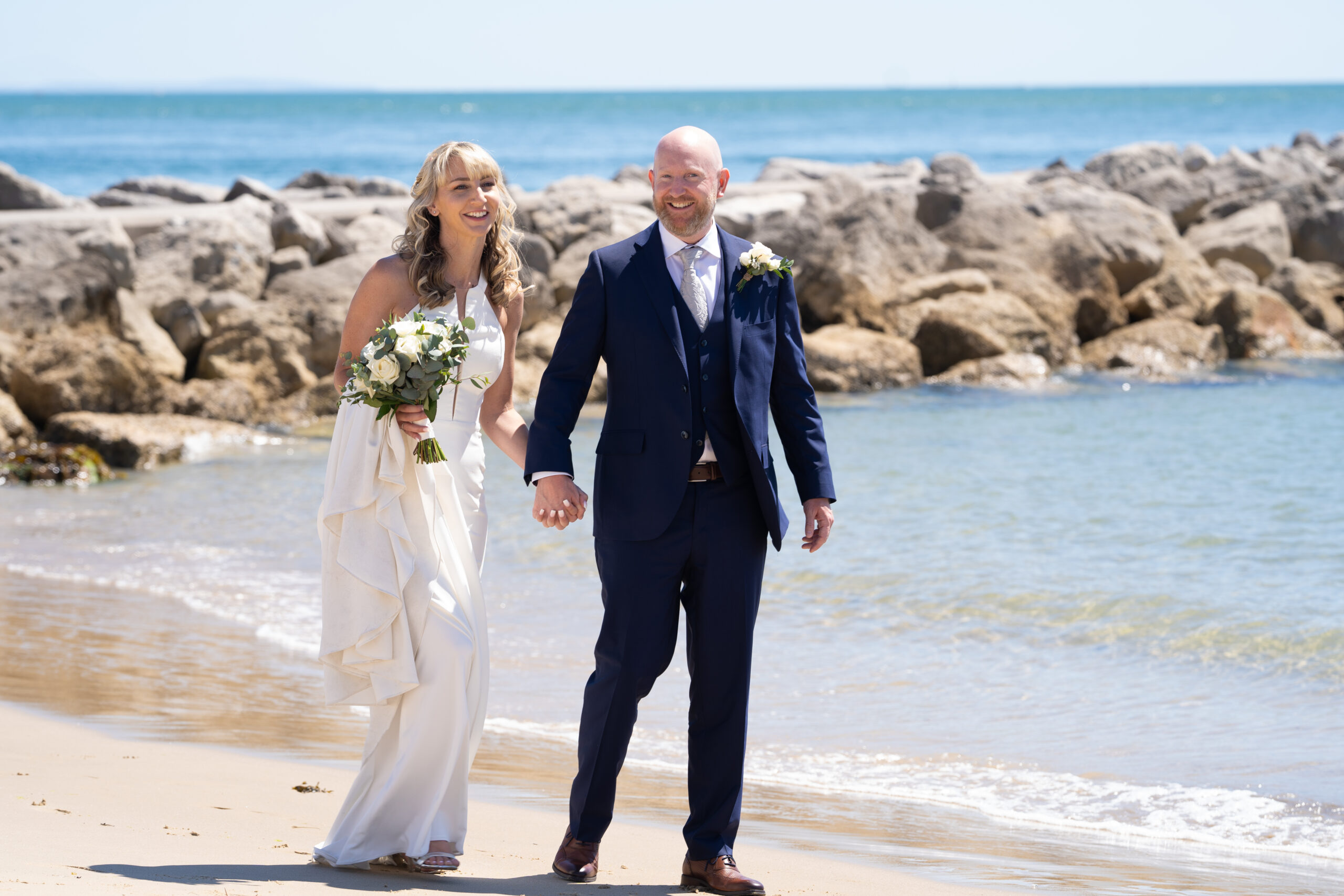 newly wed couple walking on sandbanks beach in Poole during a photoshoot with Bournemouth wedding photographer